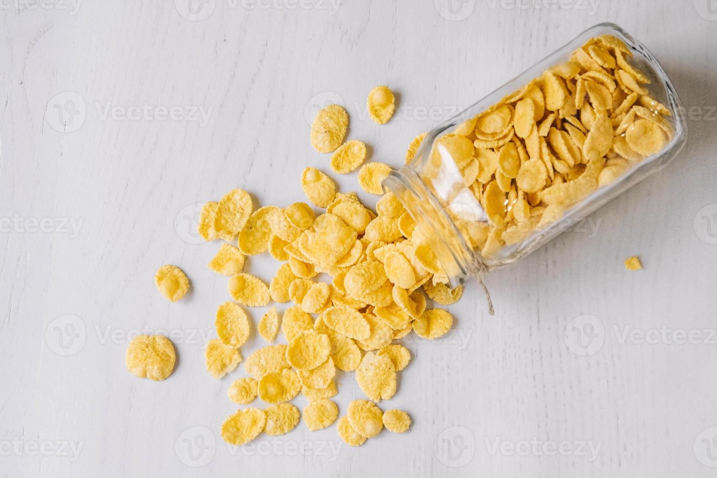 Corn flakes in a glass jar on white wooden surface photo