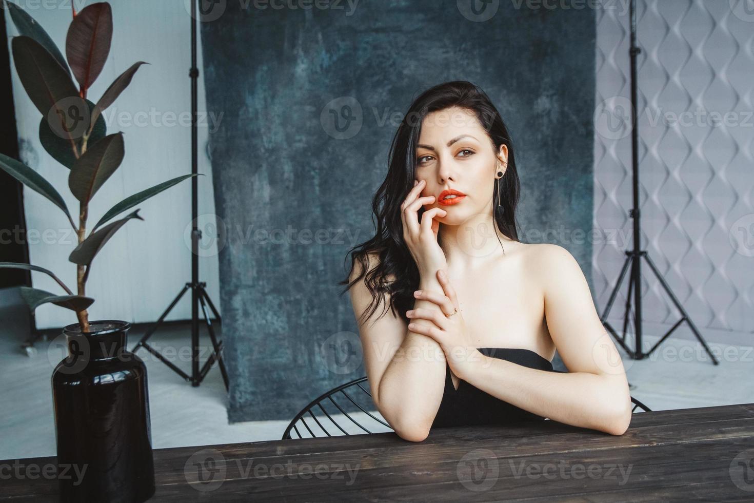 Portrait of woman sitting at table on dark gray copy space background photo