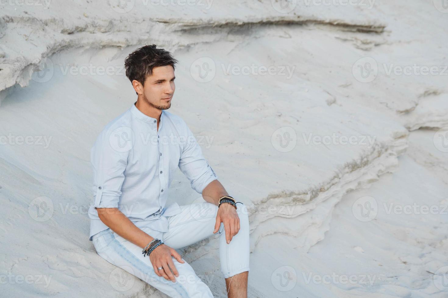 hombre con ropa ligera se sienta en el desierto foto