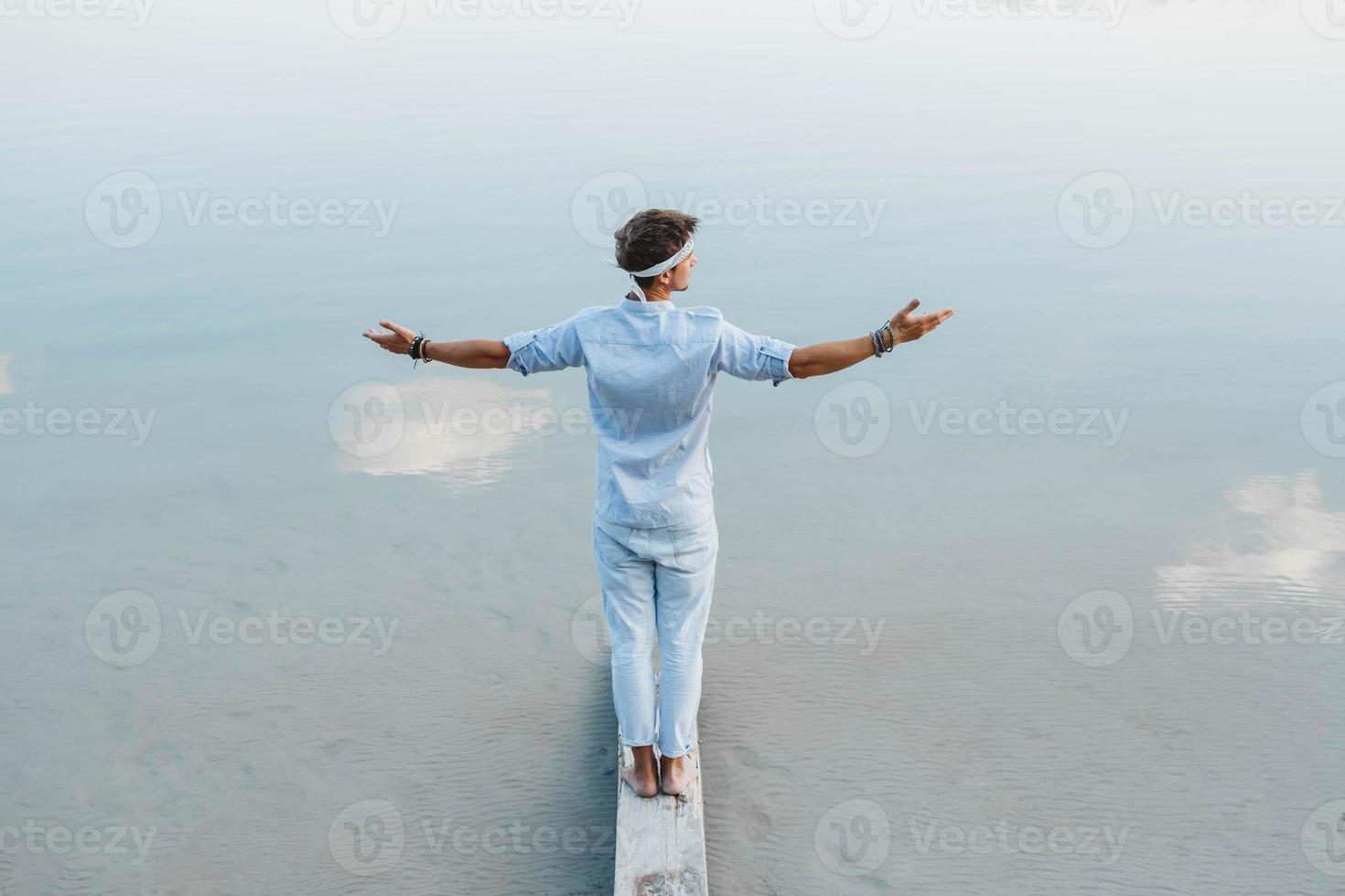 Man stands on wooden bridge and looks at water photo