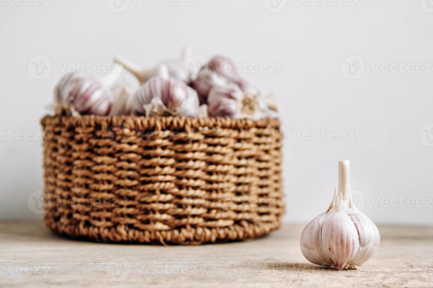 Garlic in a wicker basket on a wooden table background photo