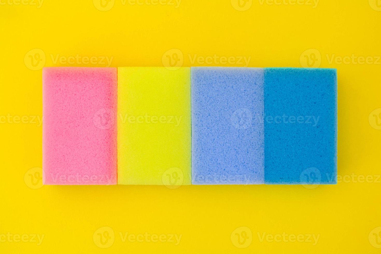 Esponja de goma espuma multicolor para limpiar y lavar platos sobre un fondo amarillo foto