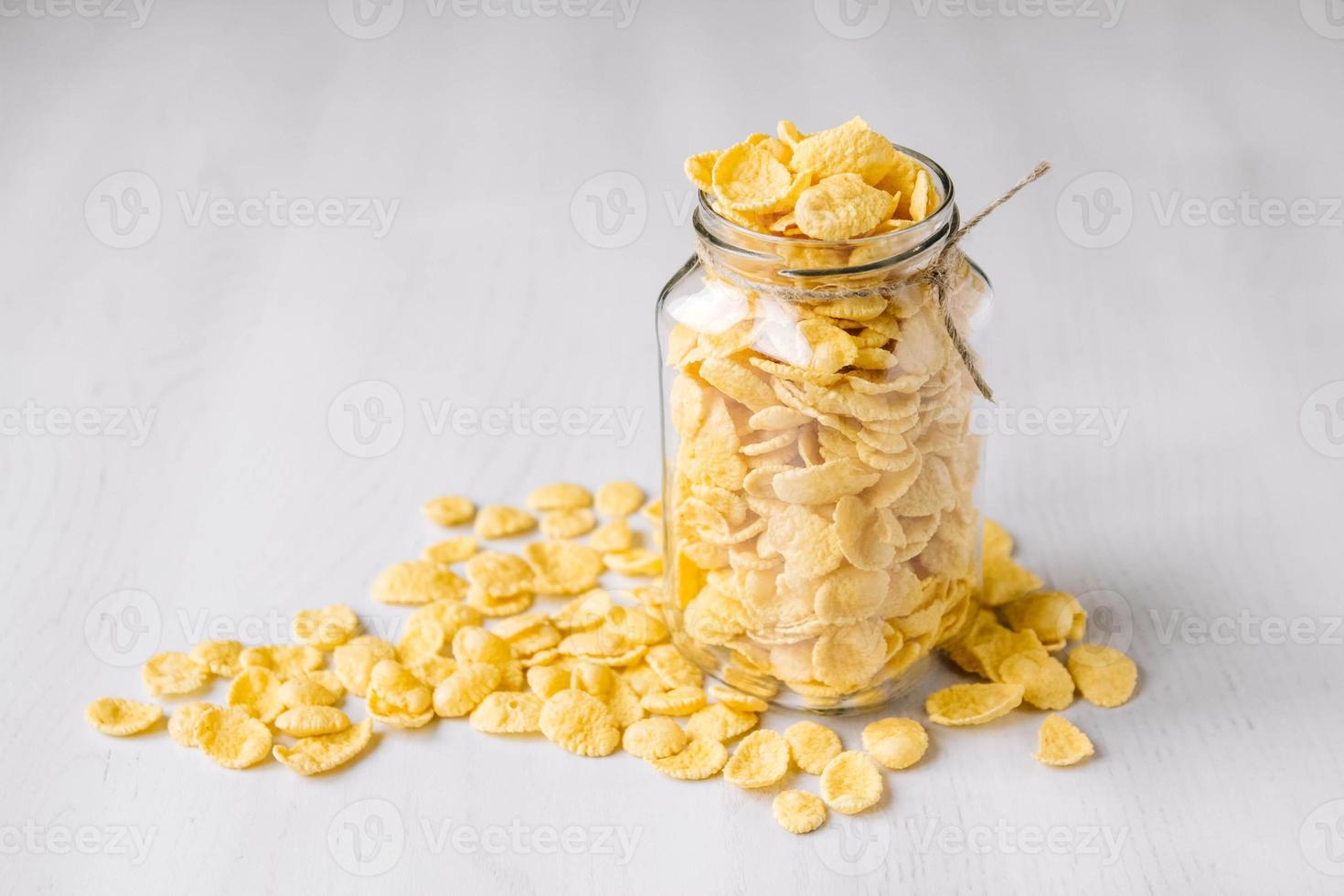 Corn flakes in a glass jar on white wooden table photo