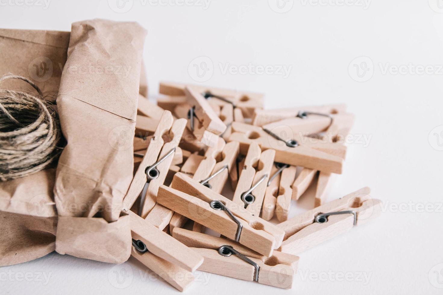 Pinzas para la ropa de madera en una bolsa de papel con una cuerda sobre fondo blanco. foto