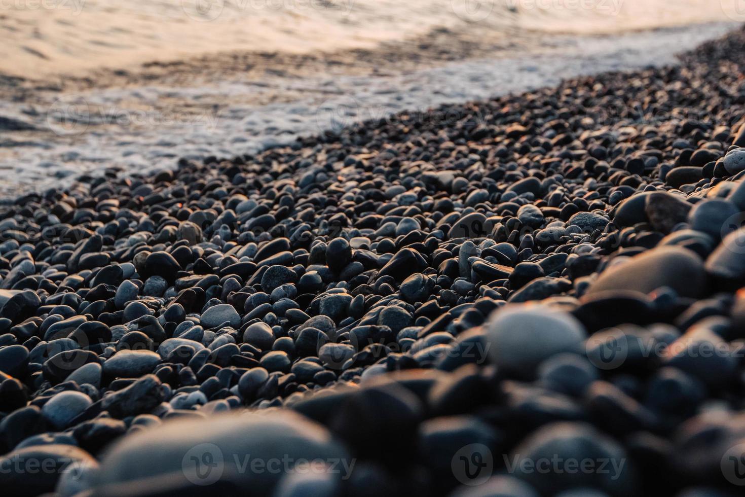 Small stones by the sea with bokeh effect. Blurred decorative background, place for text photo