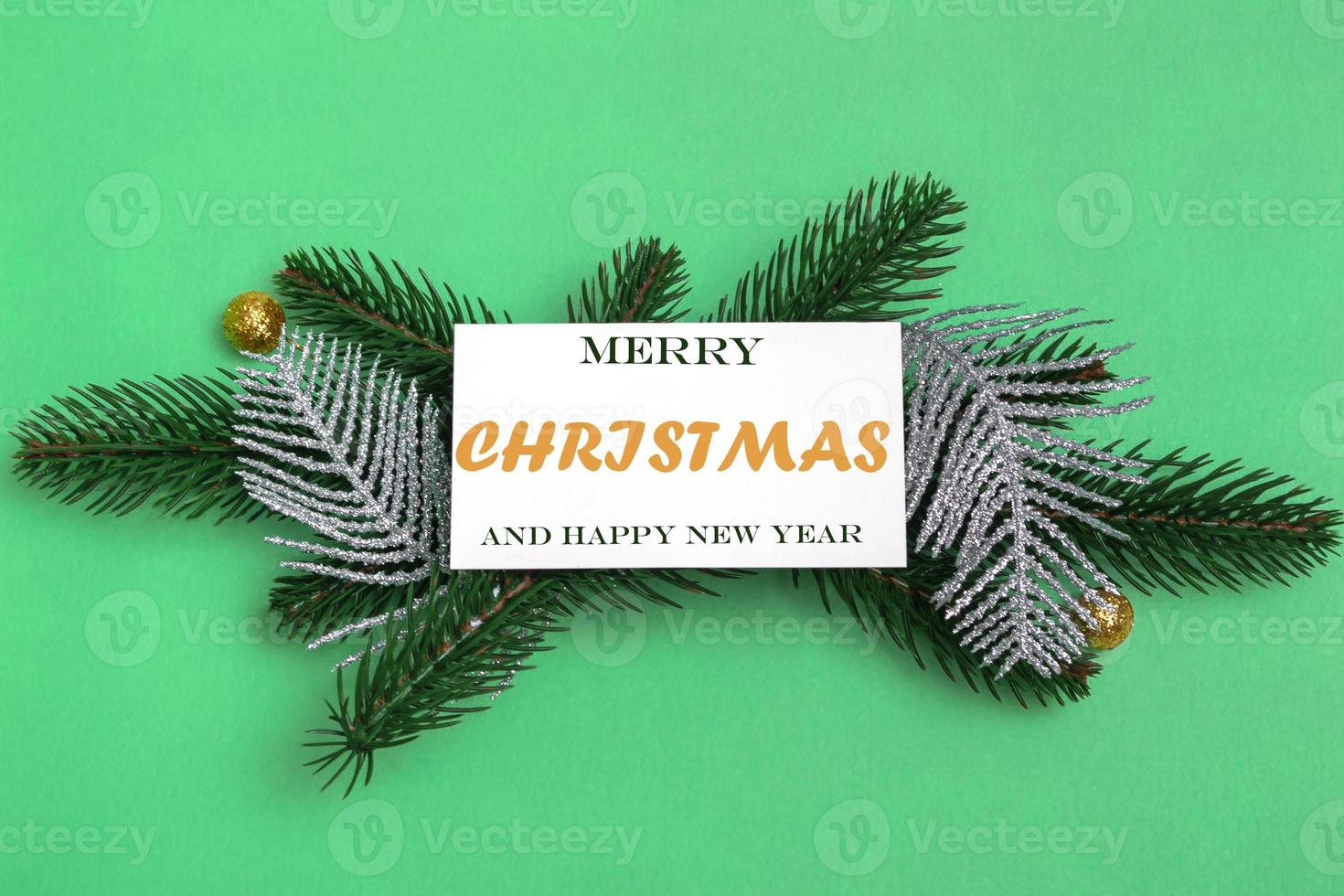 On spruce branches with Christmas decorations, a mockup of a postcard with an inscription on a colored background. Close up,copy space photo