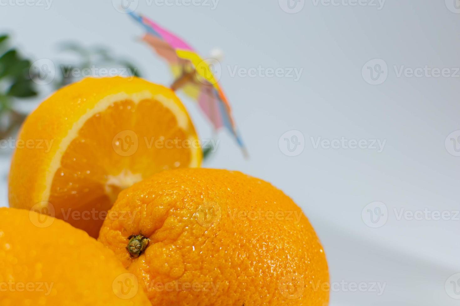Three oranges under a cooking umbrella, one orange cut in half photo