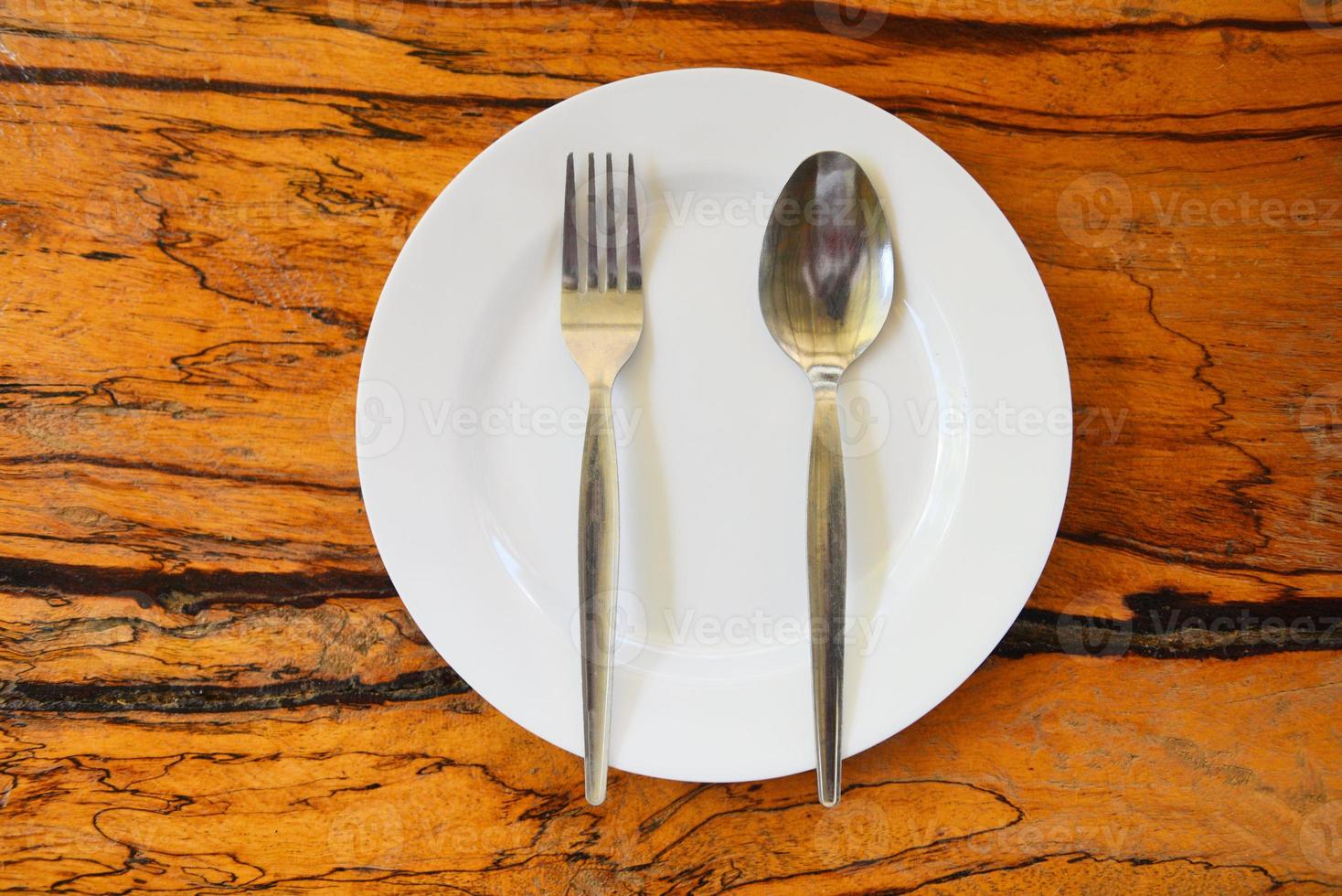 Empty plate with spoon fork on food table wooden background - empty dinner plate dish , top view photo