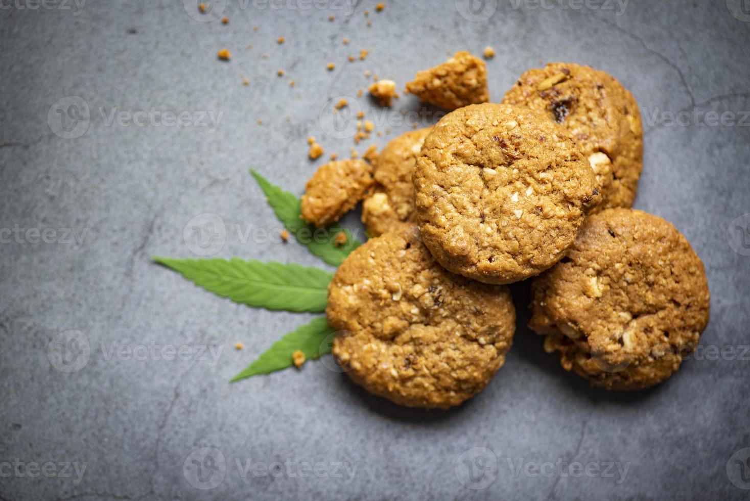 Concepto de hierba de naturaleza de comida de cannabis, galletas de chocolate con hoja de cannabis - planta de hojas de marihuana sobre fondo oscuro foto