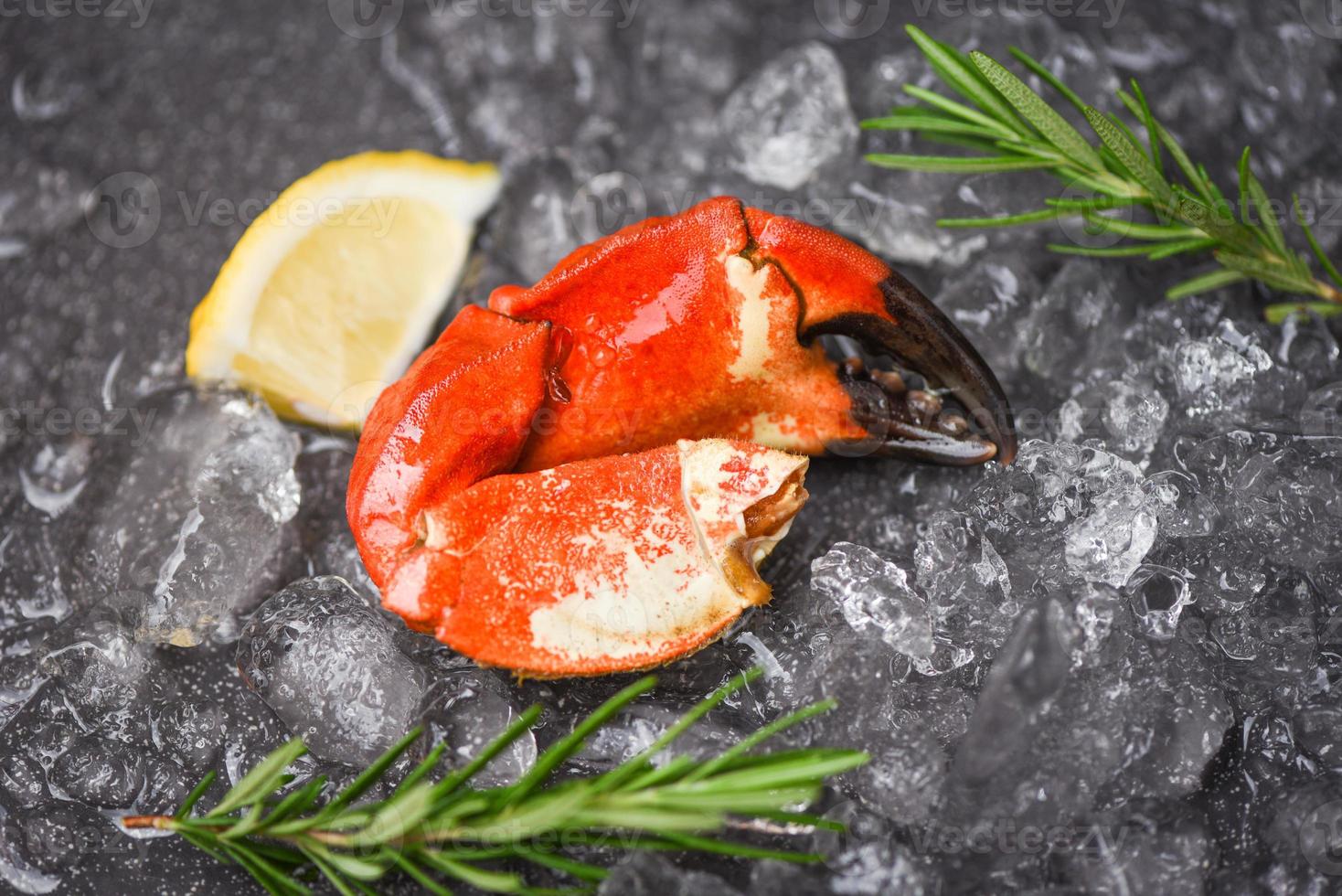 Mariscos congelados garras de cangrejo hervido - cangrejo fresco con ingredientes limón romero sobre hielo en el mercado foto