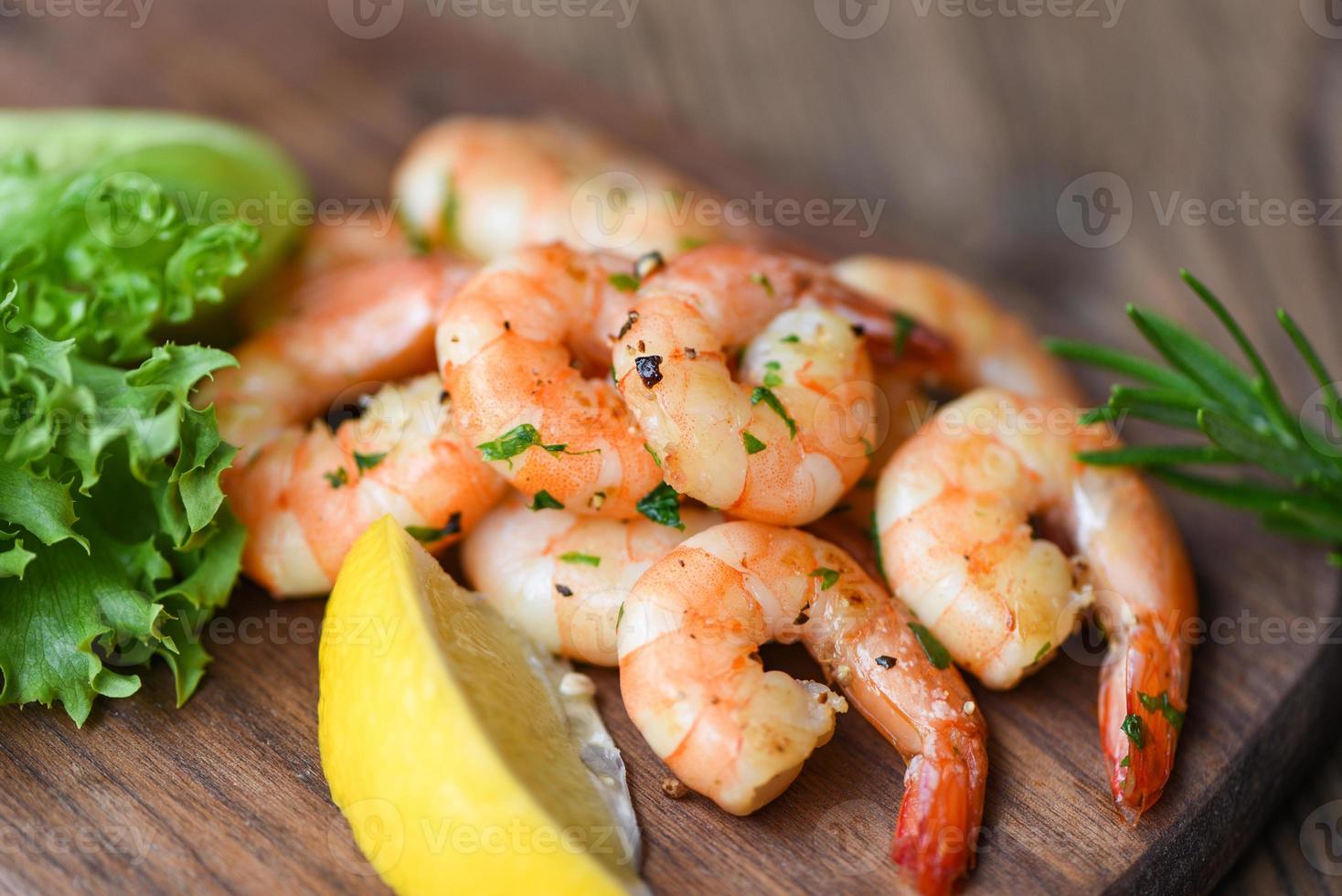 Salad shrimp grilled delicious seasoning spices on wooden cutting board background - appetizing cooked shrimps baked prawns , Seafood shelfish with rosemary lemon and lettuce photo
