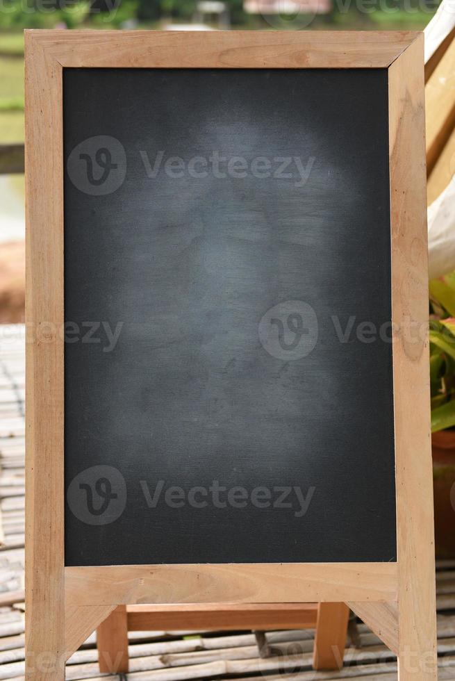 Black blackboard on wooden easel rubbed out dirty chalkboard on outdoors photo