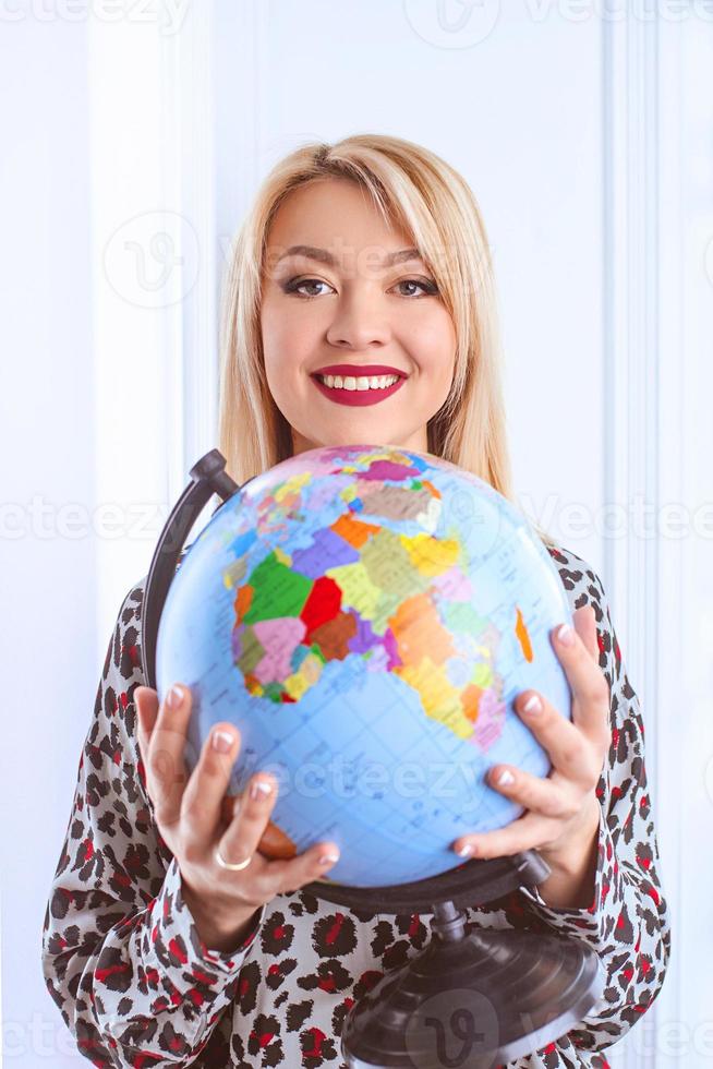 beautiful cheerful smiling blonde woman travel agent holding globe in her hands photo