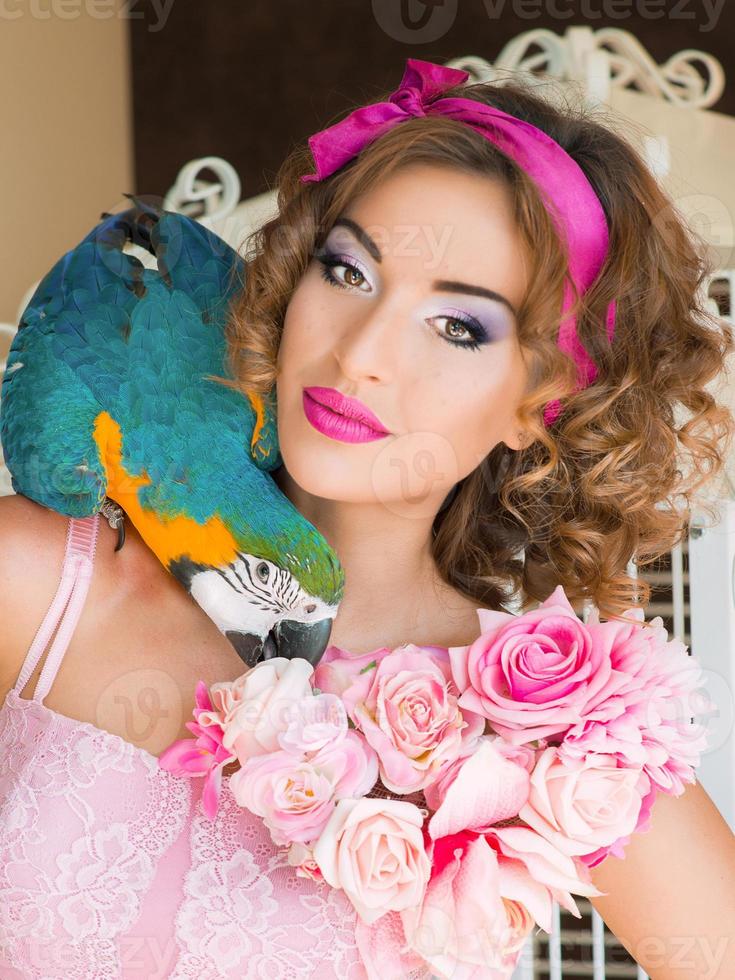 portrait of young beautiful woman in colorful dress with flowers  it in doll style with ara on her shoulder photo