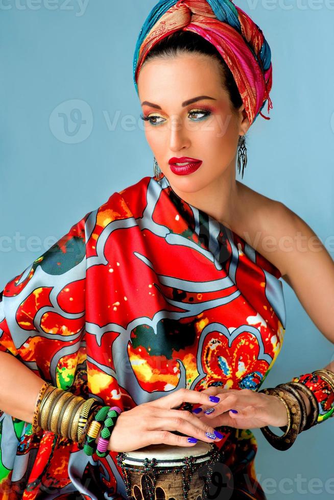 Retrato de triste mujer joven y atractiva cantante en estilo africano con tambor sobre fondo de colores foto