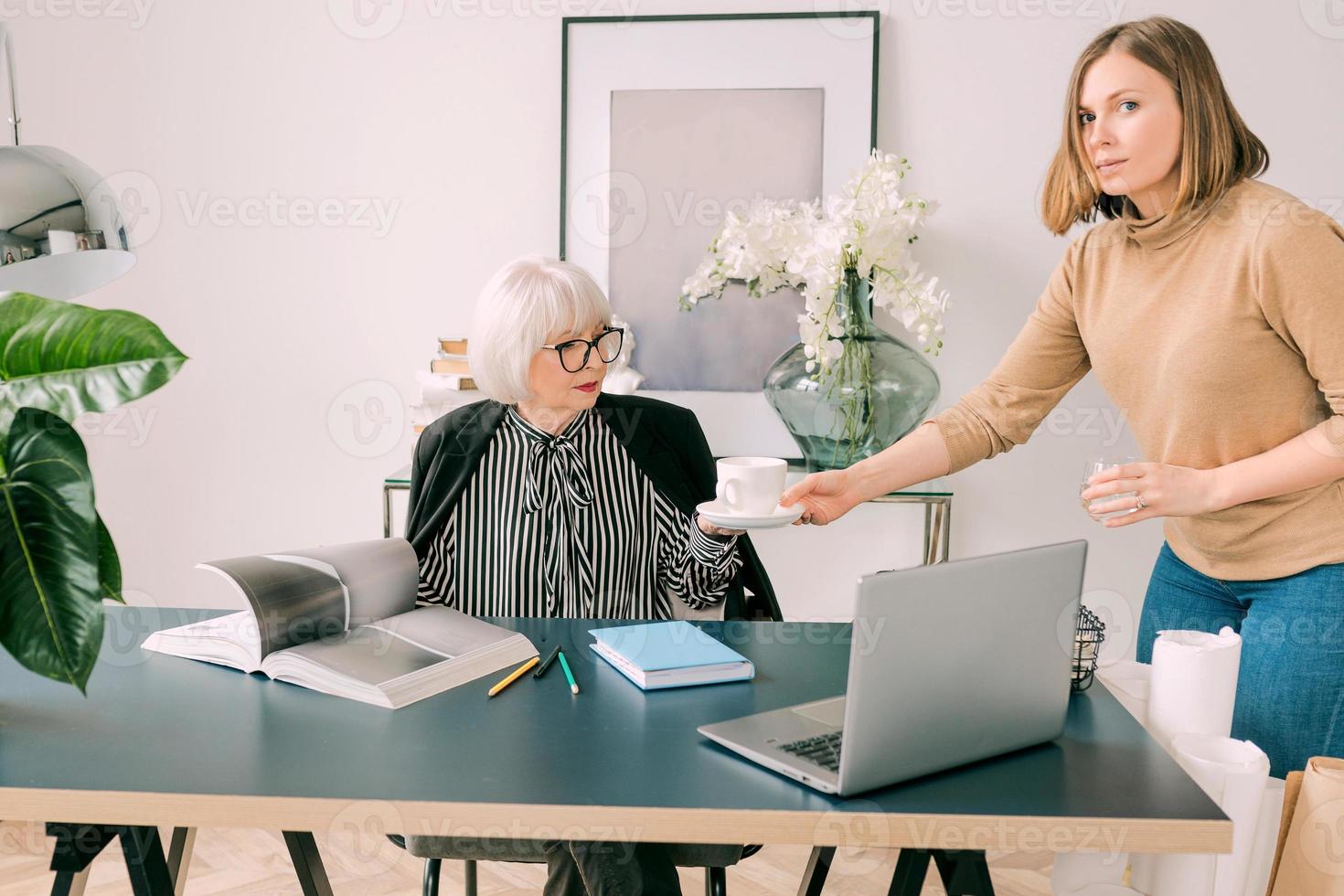 young assistant brought a coffee to the boss in office. Business, communication, work, ages, collaboration, mentoring concept photo