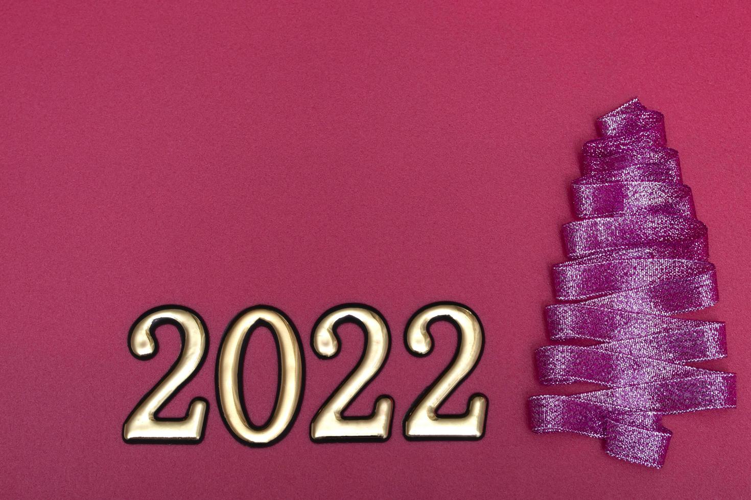 Christmas concept. Purple Christmas tree made from ribbons and gold numbers on a pink background with copy space on top. Template for postcards, packaging. photo