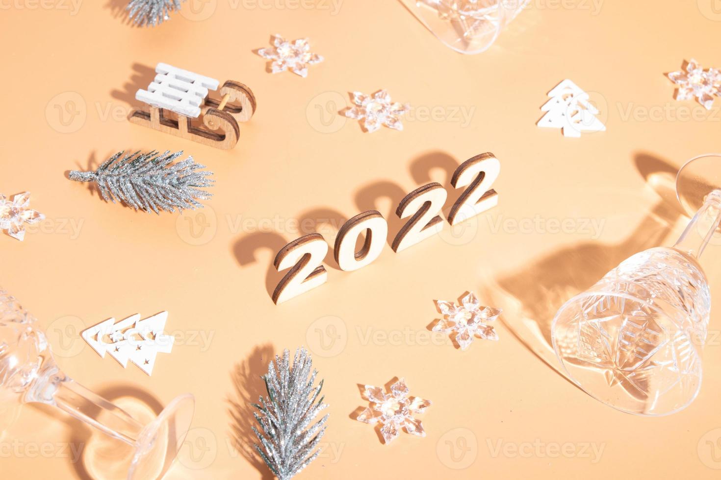 Festive new year flat lay with numbers 2022 and hard shadows with glasses and shiny decor photo