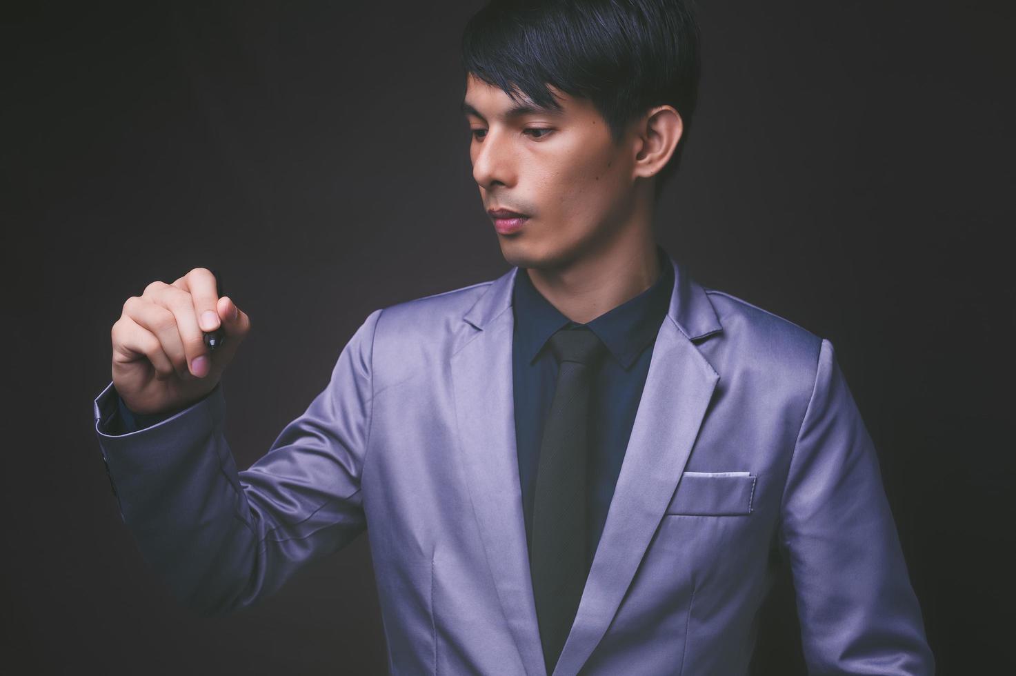 Businessman holding a pen, black background photo