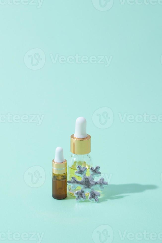 Cosmetic bottles of oil and serum with pipette with winter decor photo