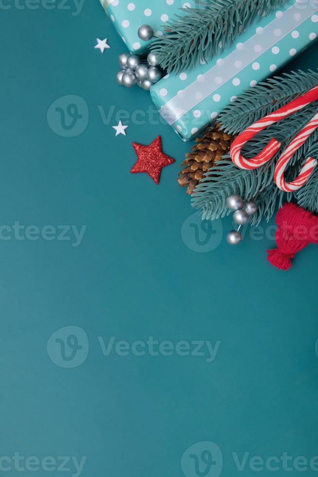 Christmas flat lay background with gifts, berries and pine on turquoise backdrop vertical format copy space photo