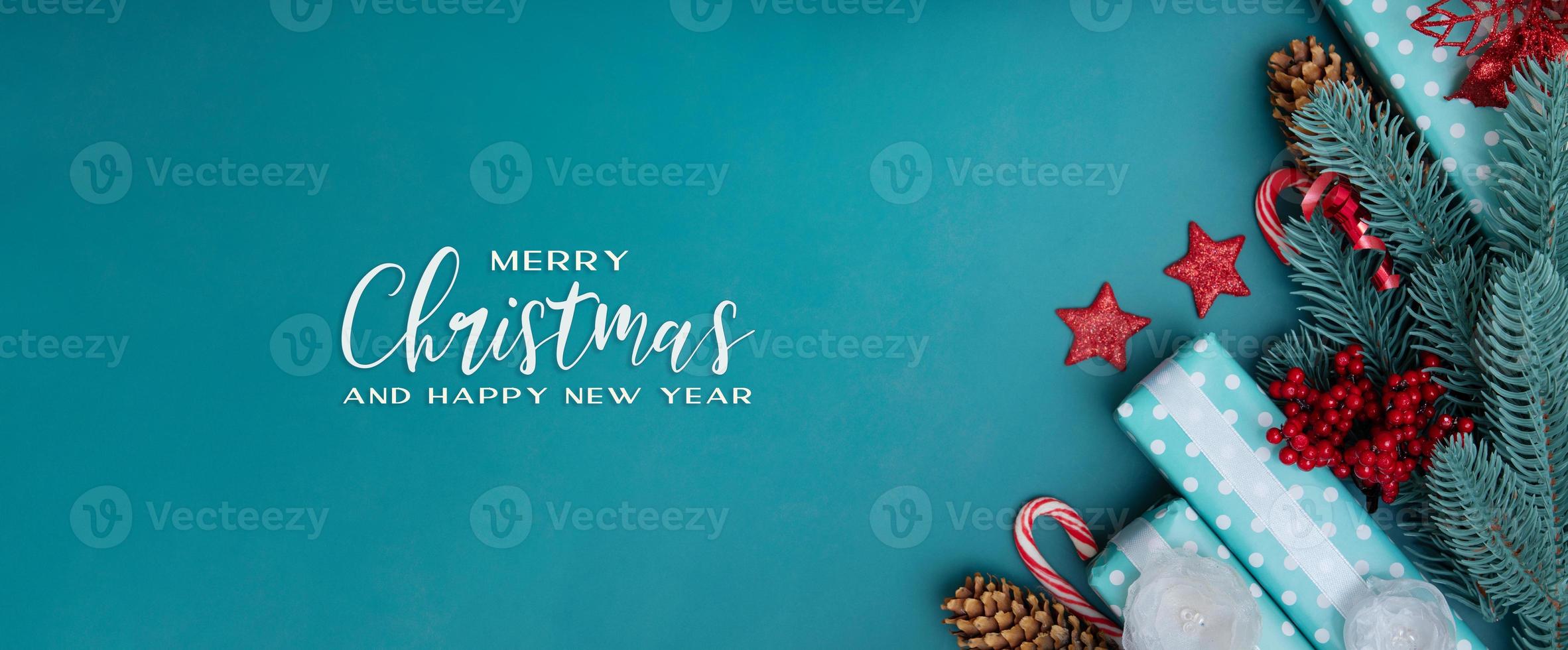 Banner de felicitación de feliz navidad con decoraciones de vacaciones de invierno laicas planas sobre fondo turquesa foto