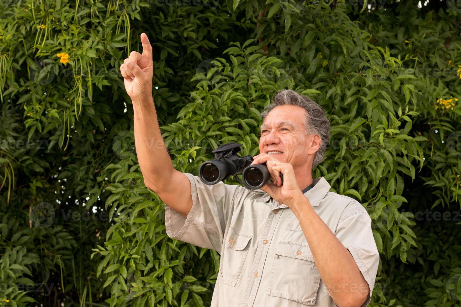 Senior Man outside enjoying nature looking through binoculars photo