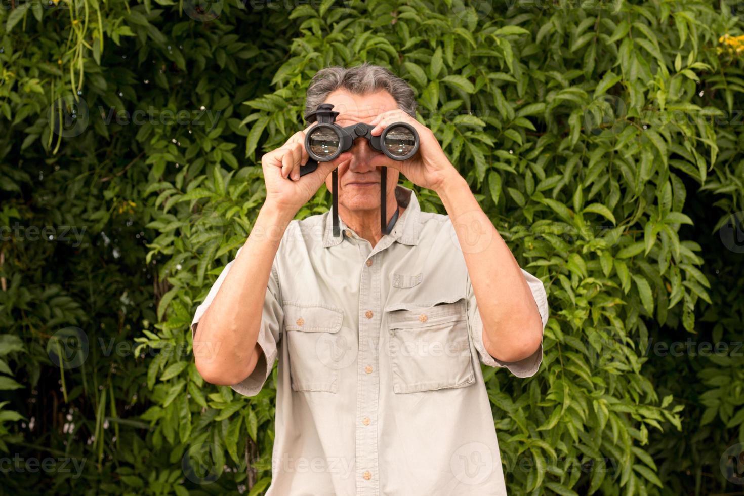 Senior Man outside enjoying nature looking through binoculars photo