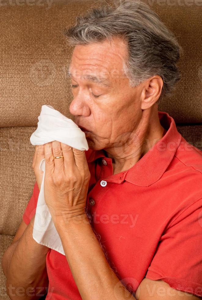 Man with the Flu Sneezing into a Handkerchief at his House photo