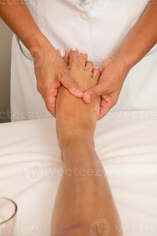 terapeuta de masaje masajeando un pie de señoritas foto