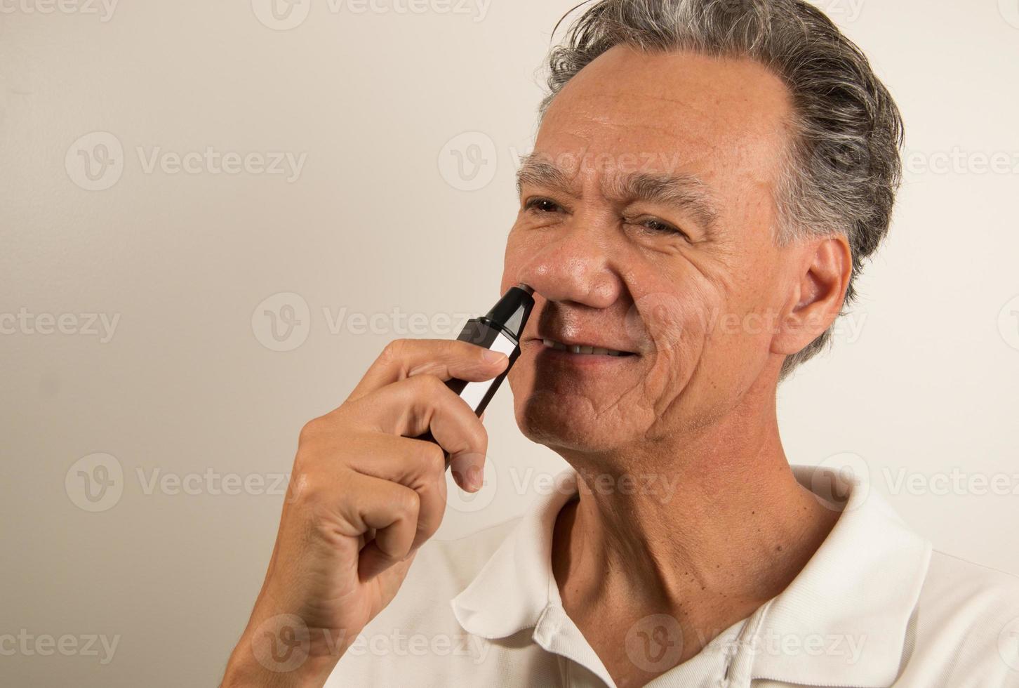 Hombre recortándose los pelos de la nariz con una recortadora de vello nasal foto