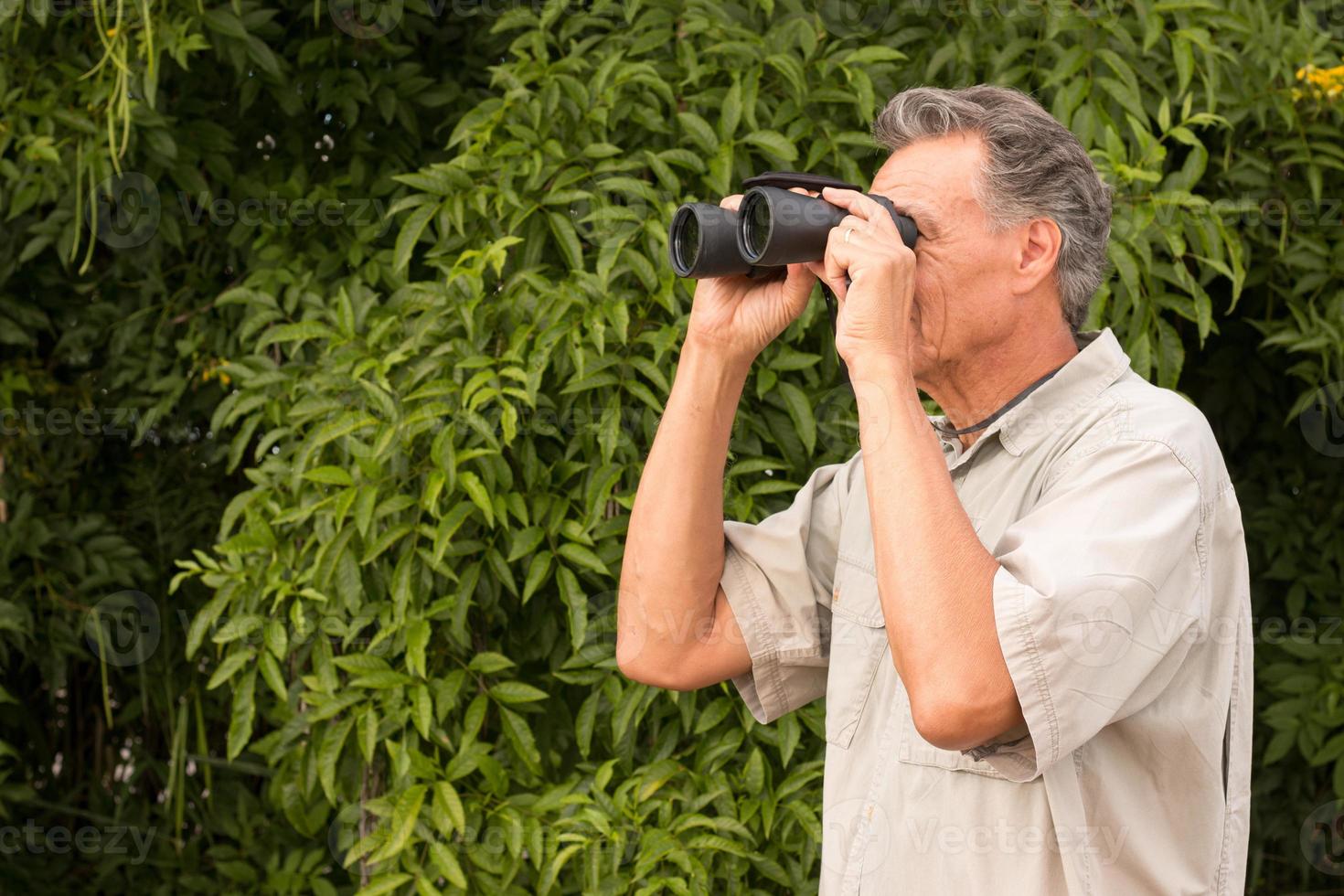 Senior Man outside enjoying nature looking through binoculars photo