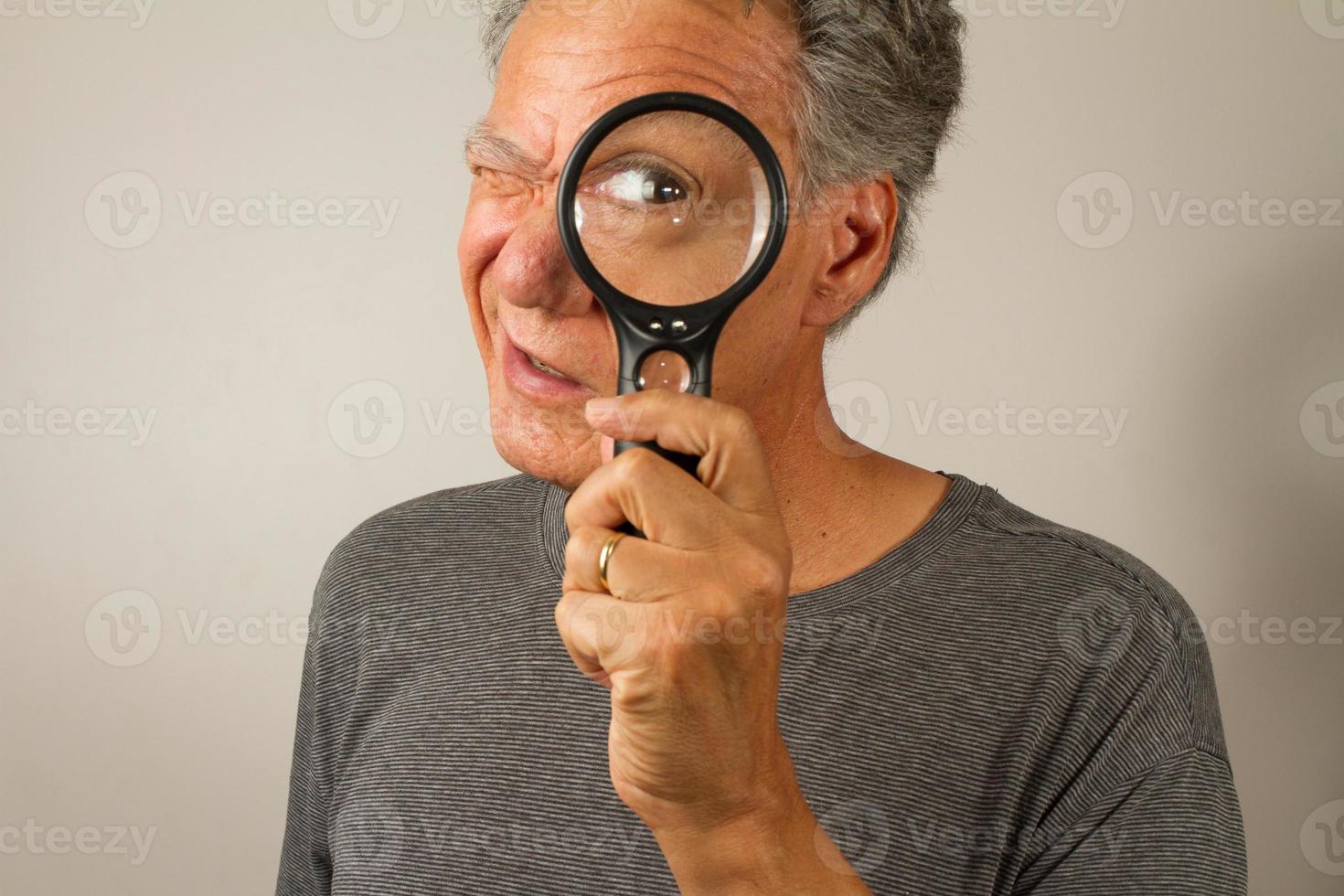 Senior Man looking through a Magnifying Glass photo