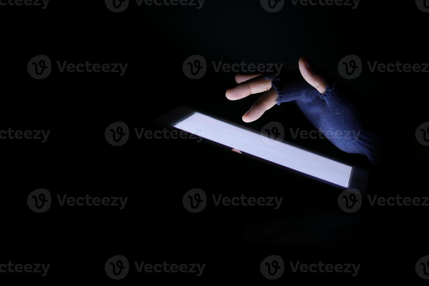 Close up of hacker hand stealing data from digital tablet photo