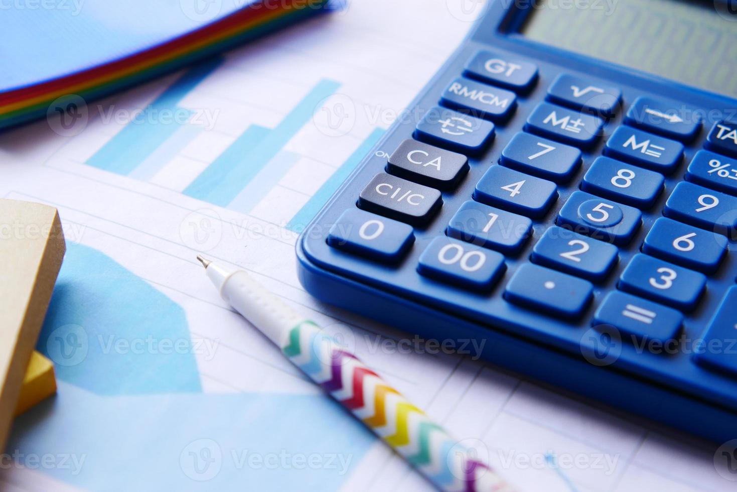 Close up of blue calculator and financial chart on table. photo