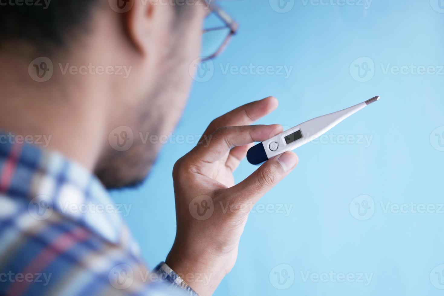 Vista trasera de la mano del hombre sostenga un termómetro digital foto