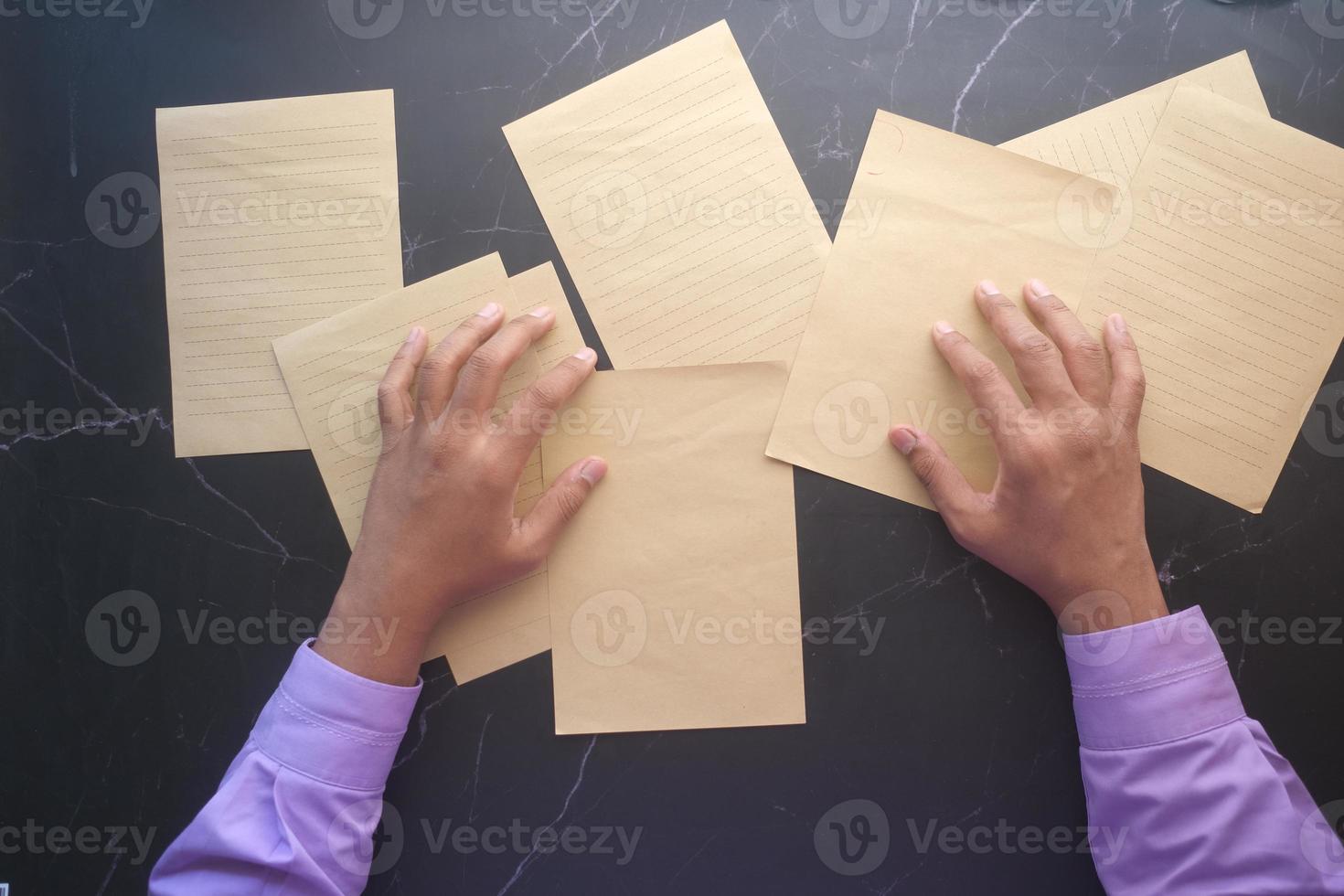 Vista superior de la mano del joven msn en papel en blanco sobre la mesa foto