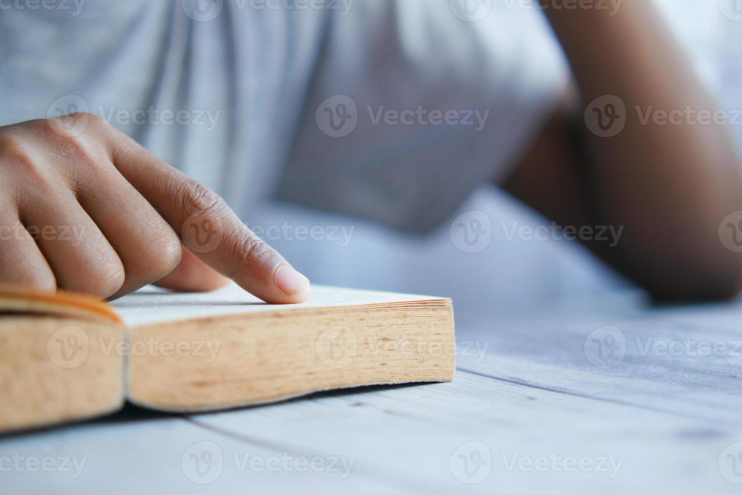 Cerca de la mano del joven leyendo un libro foto