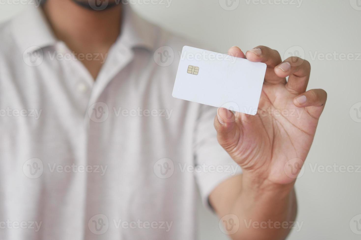 hombre en traje casual mostrando tarjeta de crédito foto