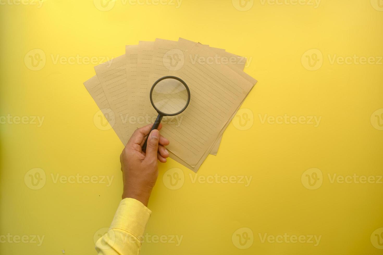 papel vacío y sosteniendo una lupa sobre la mesa. foto