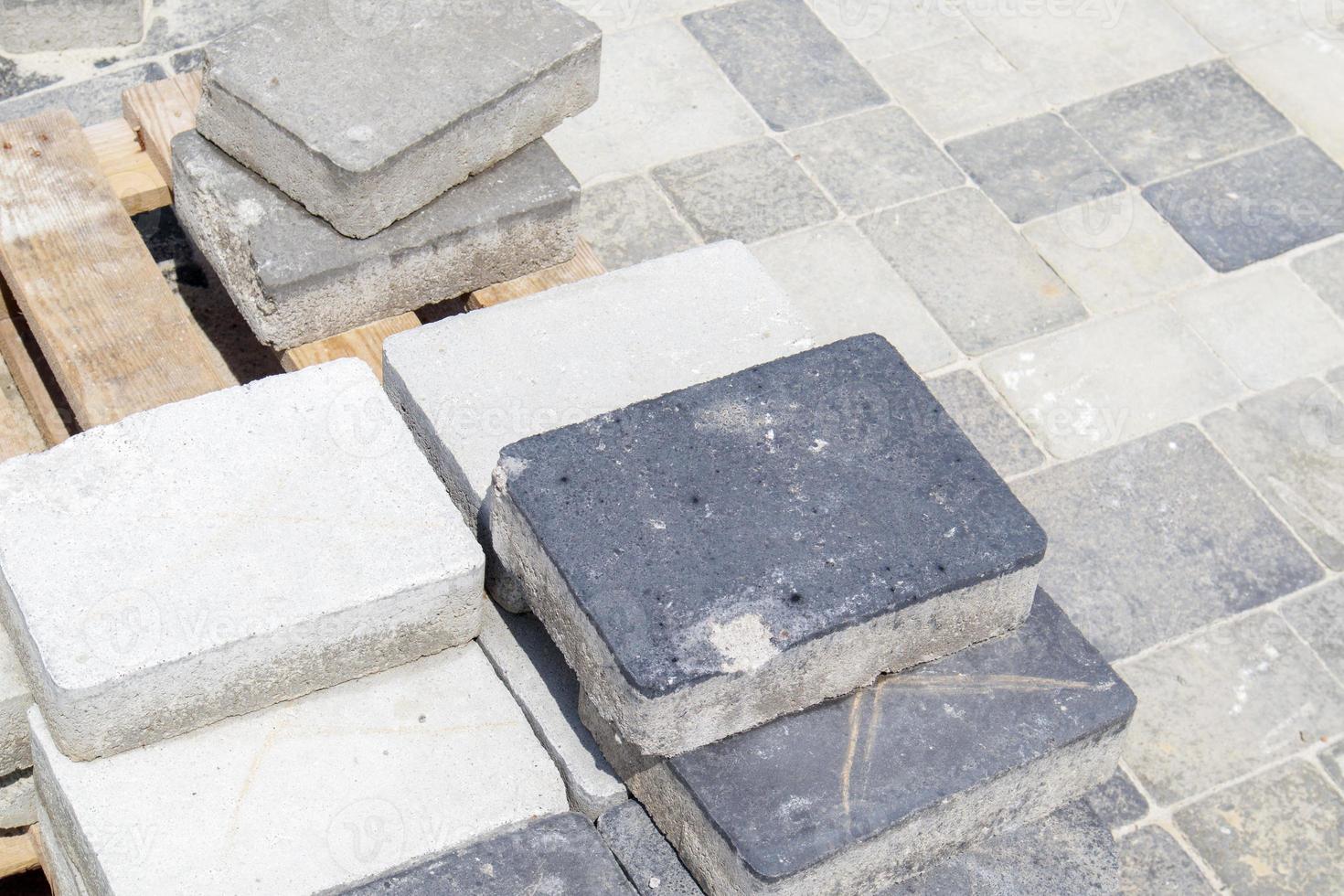 Concrete or paved gray paving slabs or floor or walkway stones stacked on a pallet. Concrete paving slabs in the backyard or road paving. Garden brick path in the courtyard on a sandy foundation. photo