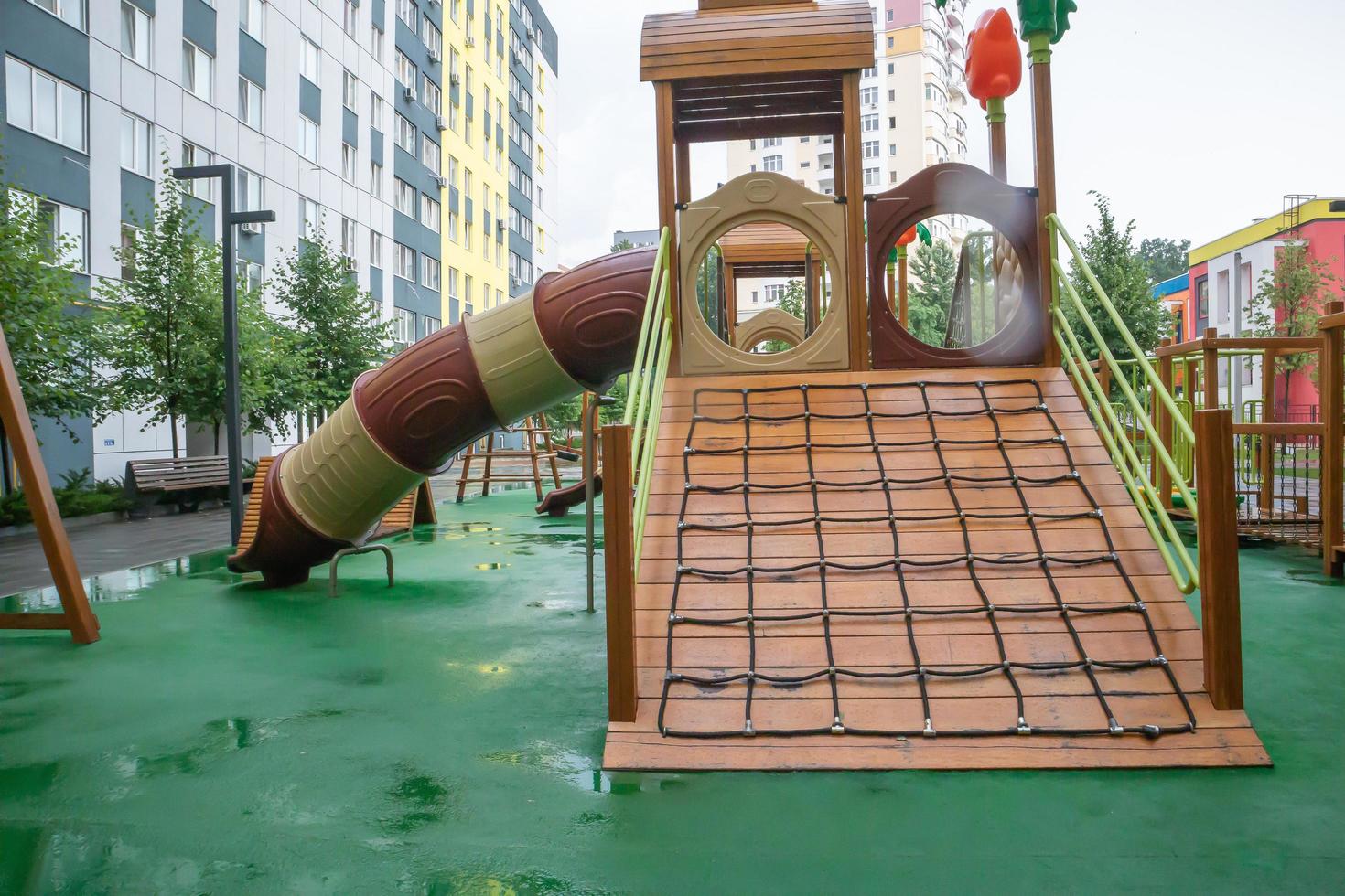 The courtyard of a high-rise building with a modern large playground made of wood and plastic on a rainy summer day without people. Ukraine, Kiev - August 19, 2021. photo