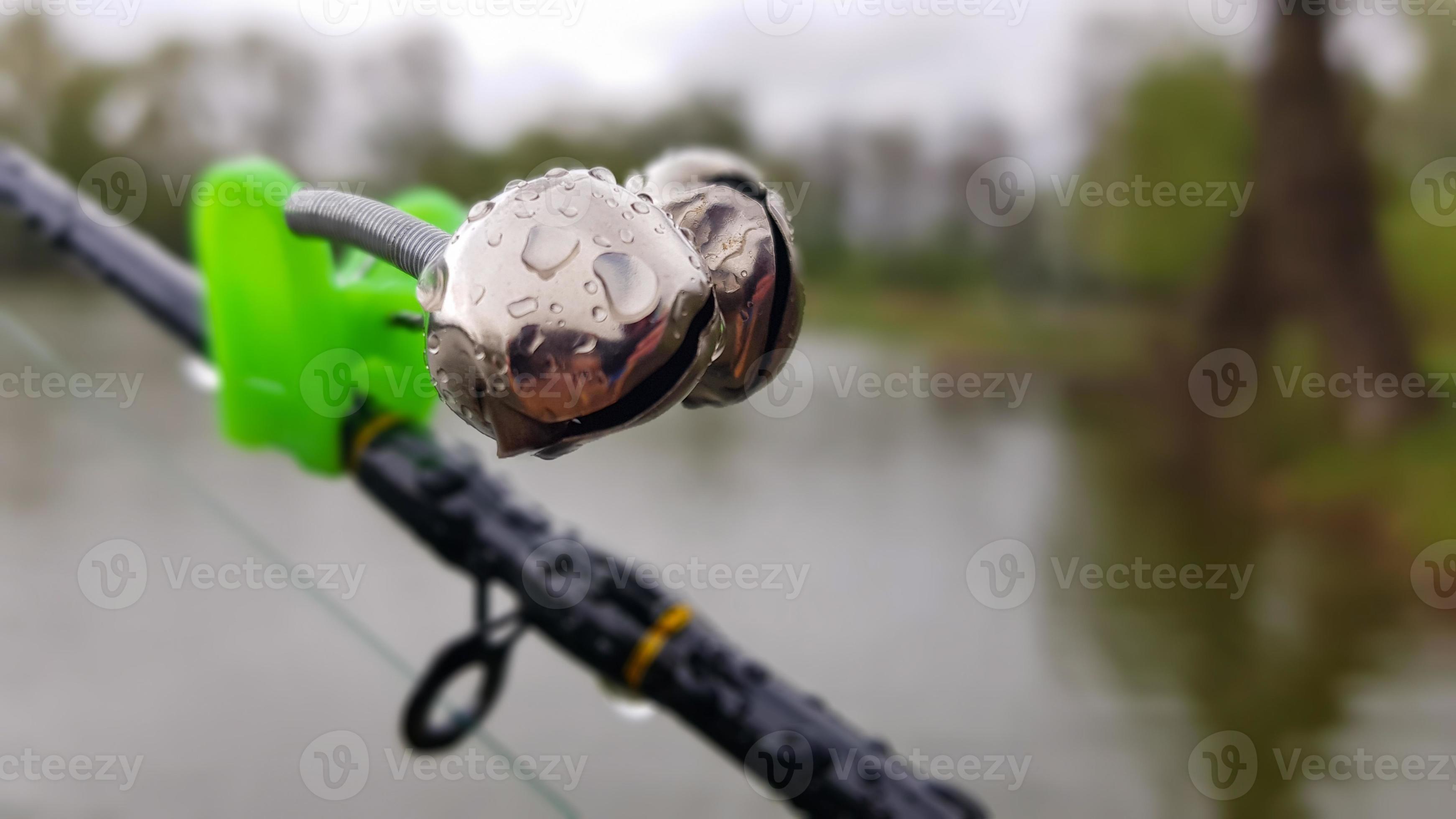 Silver fishing bells are worn on a fishing rod while fishing. Bite-call  signal, at the tip of the rod. A bite alarm will alert you to a bite.  Fishing tackle close-up. 4536051