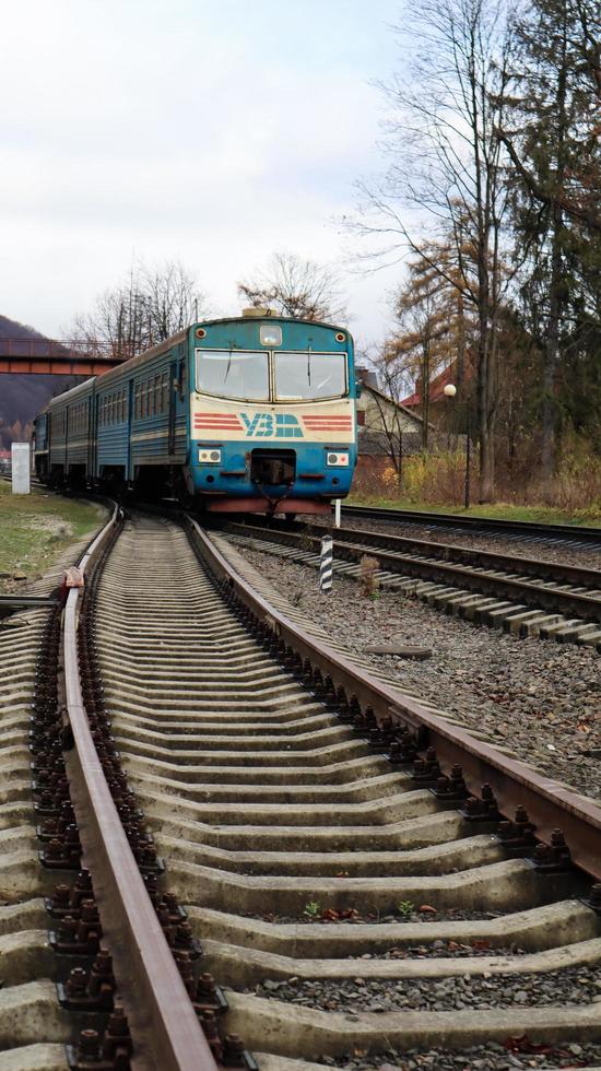 Ucrania, Yaremche - 20 de noviembre de 2019. Tren en la estación sobre un fondo de montañas. vagones de ferrocarril únicos en el andén de la ciudad de yaremche. Antiguo tren de pasajeros diesel. estación de ferrocarril. foto