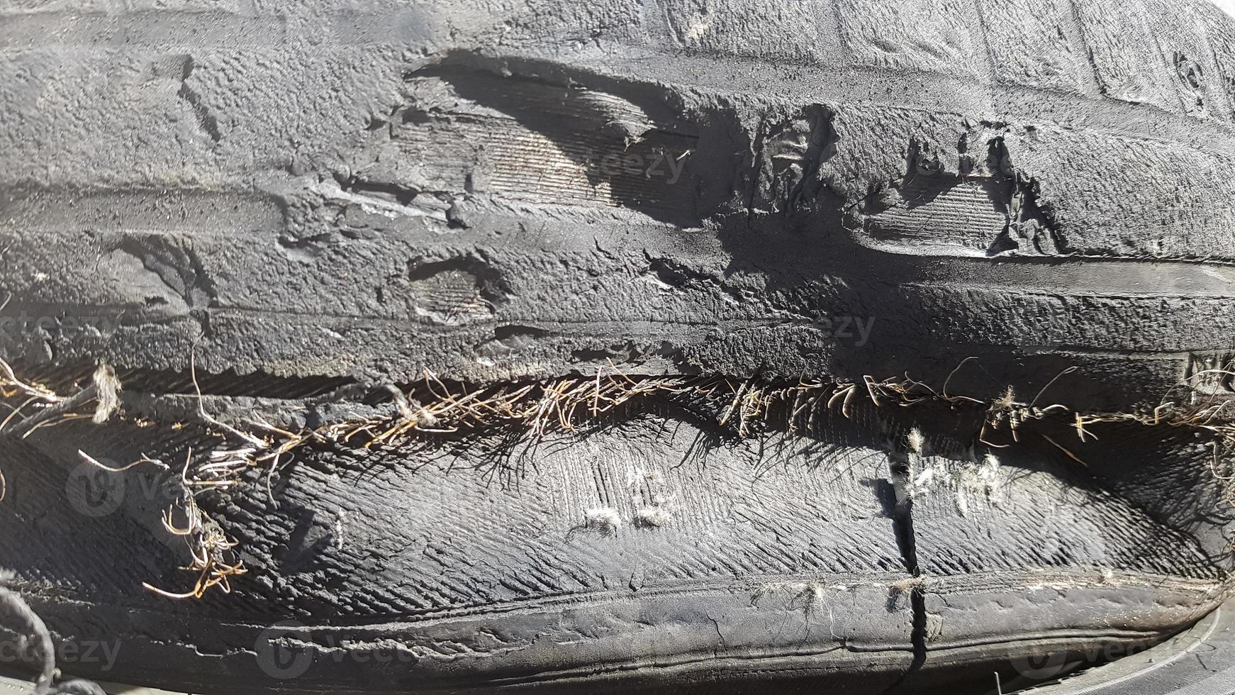 A tire that is damaged after prolonged use. A worn-out and torn car tire in a junkyard. photo