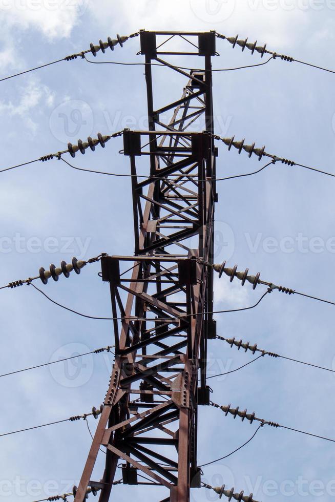 Torre eléctrica de alta tensión. Líneas eléctricas y torres de energía en un día soleado con nubes circulares en el cielo azul. Soportes de línea de transmisión de energía de alto voltaje. tienen una estructura de acero compleja. foto