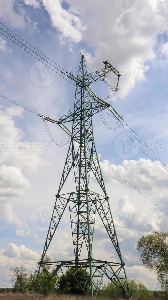 One tower, high voltage power lines. High voltage cables. High voltage electrical tower on the field. against the blue sky. Vertical photography. photo