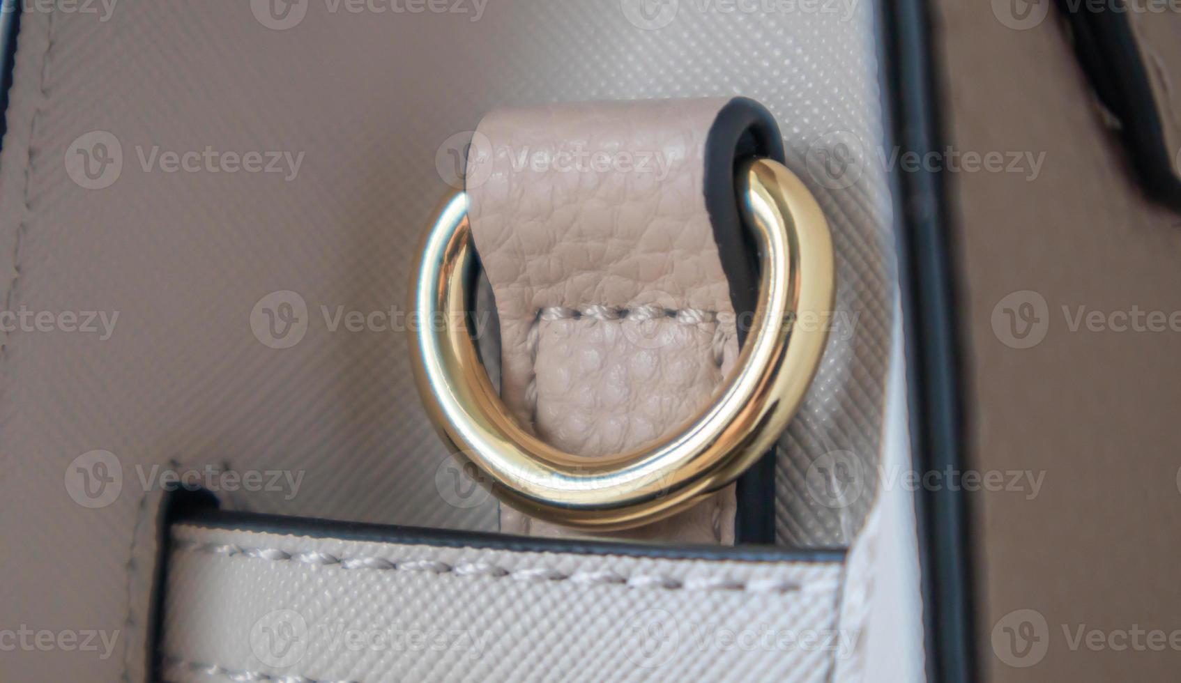 Metal gold loop oval ring attached to a leather bag. Selective focus. Part for a secure connection between two objects. Sewing accessories in the form of a ring for sewing bags, glossy. photo