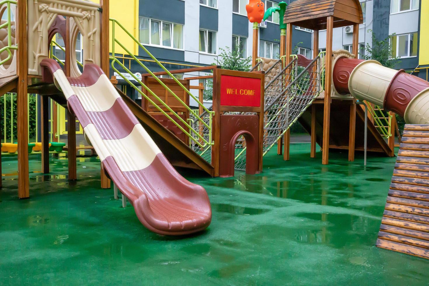 el patio de un edificio de gran altura con un gran parque infantil moderno de madera y plástico en un día lluvioso de verano sin gente. Ucrania, Kiev - 19 de agosto de 2021. foto