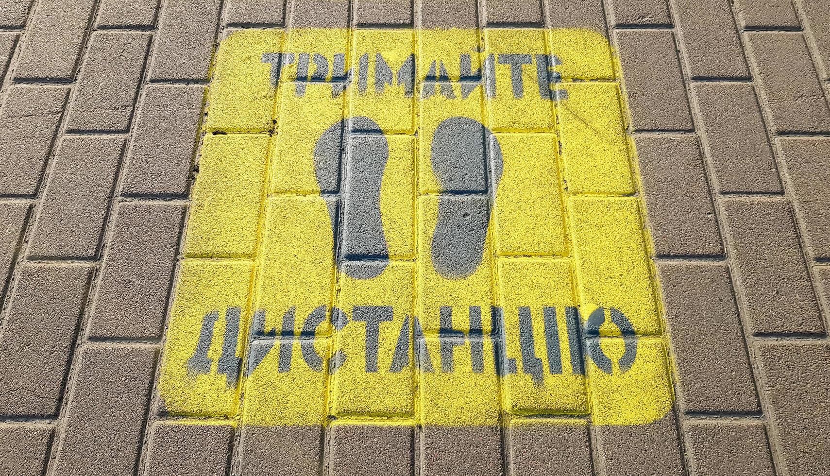 Ukraine, Kiev - April 23, 2020. Yellow sidewalk with the warning Keep your distance on the sidewalk. The text is in Ukrainian. Concept of maintaining social distance, quarantine or isolation photo